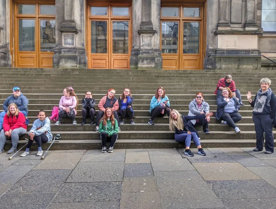 Several students sitting on steps outside an old building in Scotland.
